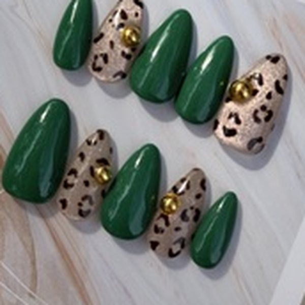 Ten almond press-on nails alternating glossy emerald green and beige leopard print with gold studs